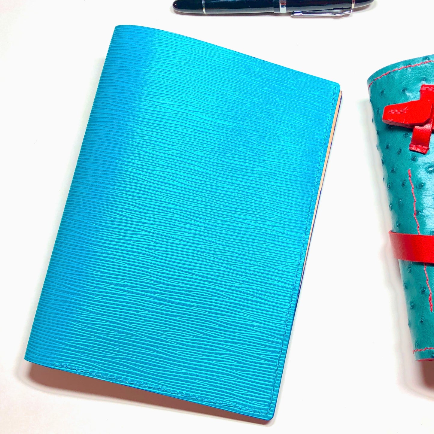 Blue textured notebook with a pen on a white background