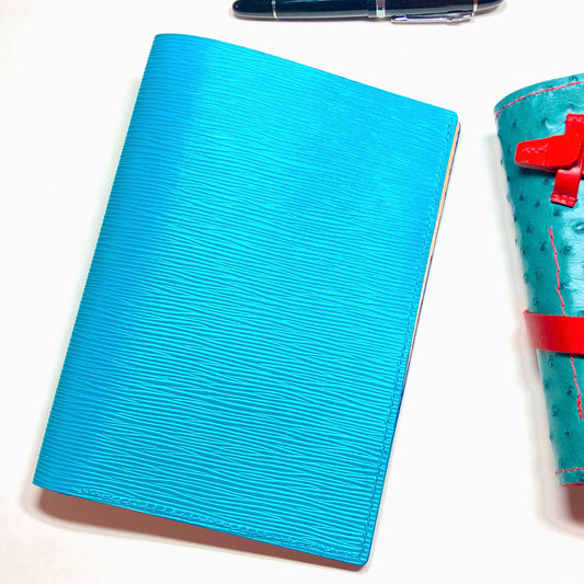 Blue textured notebook with a pen on a white background