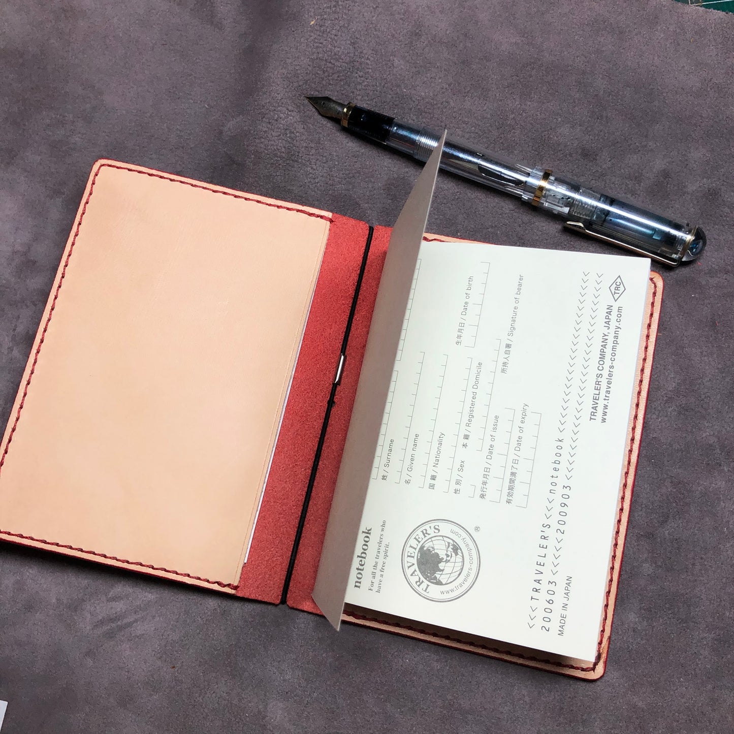 Inside of a Red cowhide leather Passport size Travelers Journal cover.  Hand stitched, finished edges. One Midori Travelers Notebook Journal included.  Refillable, pocket-size. 