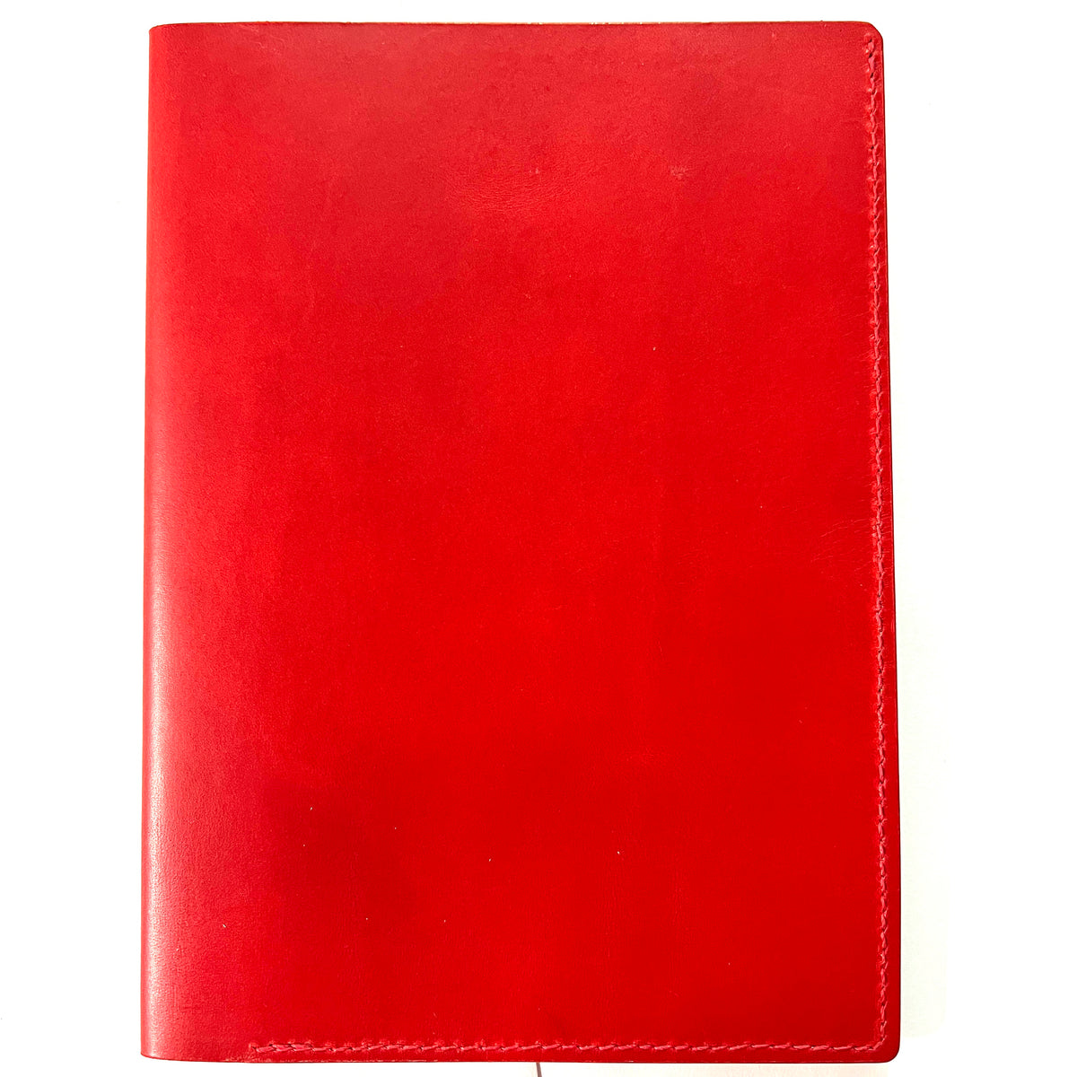 A red leather notebook cover or planner cover with visible stitching along the right edge, shown flat against a white background.