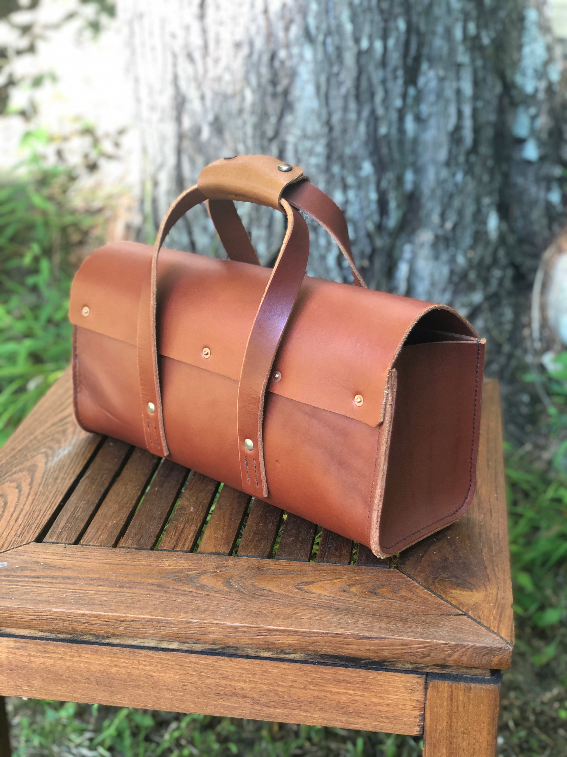 Brown leather tool bag on a wooden surface with a natural background