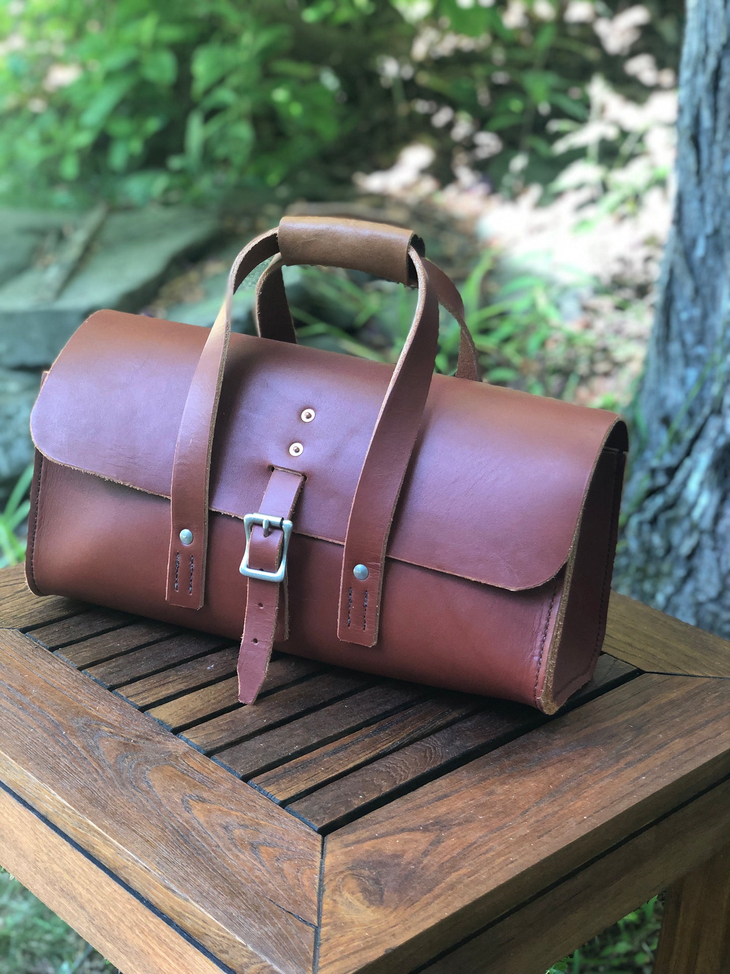 Chestnut brown leather tool bag on a wooden surface with a natural background