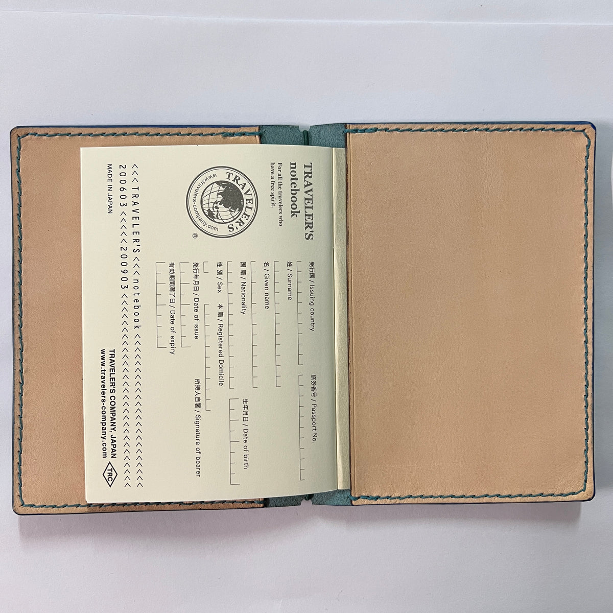 An open leather travelers' portbook with a tan interior page, a blank tan back cover, and a cream-colored Japanese passport insert on a white background.
Cowhide leather Passport size Travelers Journal cover.  Hand stitched, finished edges. One Midori Travelers Notebook Journal included.  